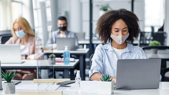 employees wearing masks working on remote desktops